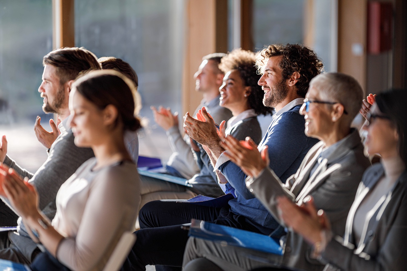 Large group of happy entrepreneurs applauding on a seminar in board room.